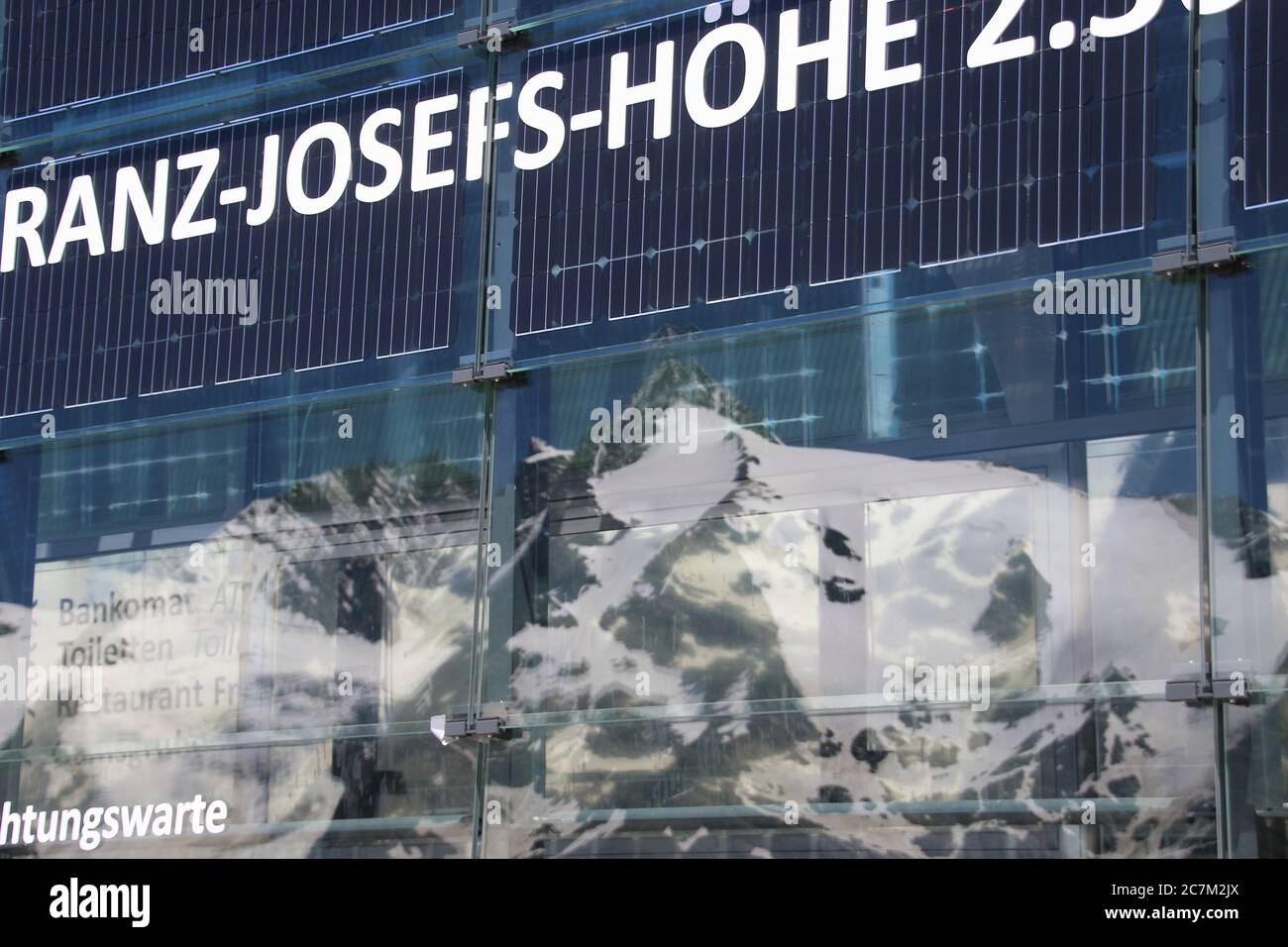 Grossglockner mountain massif: Viewing terrace of the visitor centre, height 2369 m. Mountains reflect in a glass facade. Austria, Europe. Stock Photo