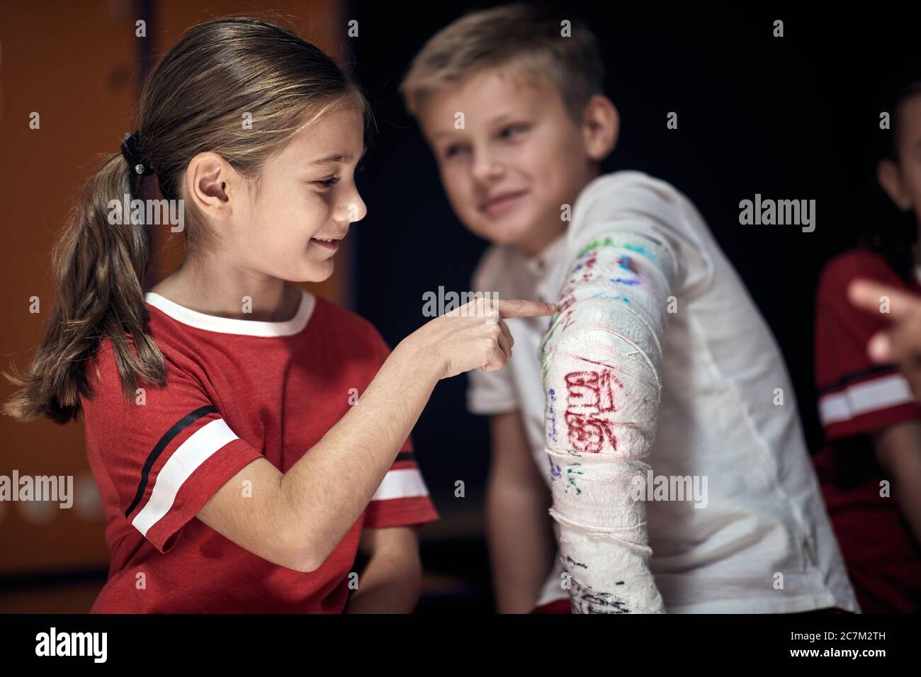 Young boy with broken arm wrapped medical cast plaster in changing room. Stock Photo