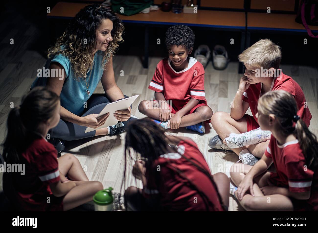 Pupil soccer team listening to coach in circlei n locker room Stock Photo