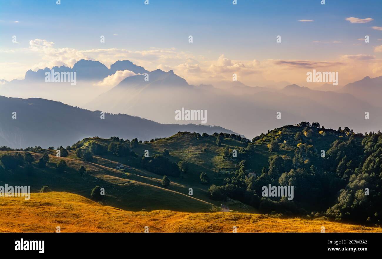 Sunset on countryside and mountains against blue sky and clouds Stock Photo