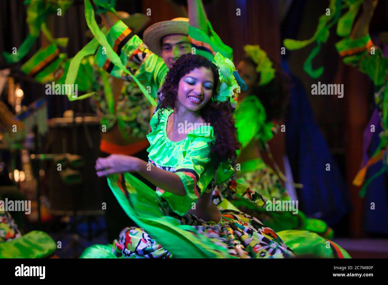 A young girl in traditional dress and other dancers dance at a local
