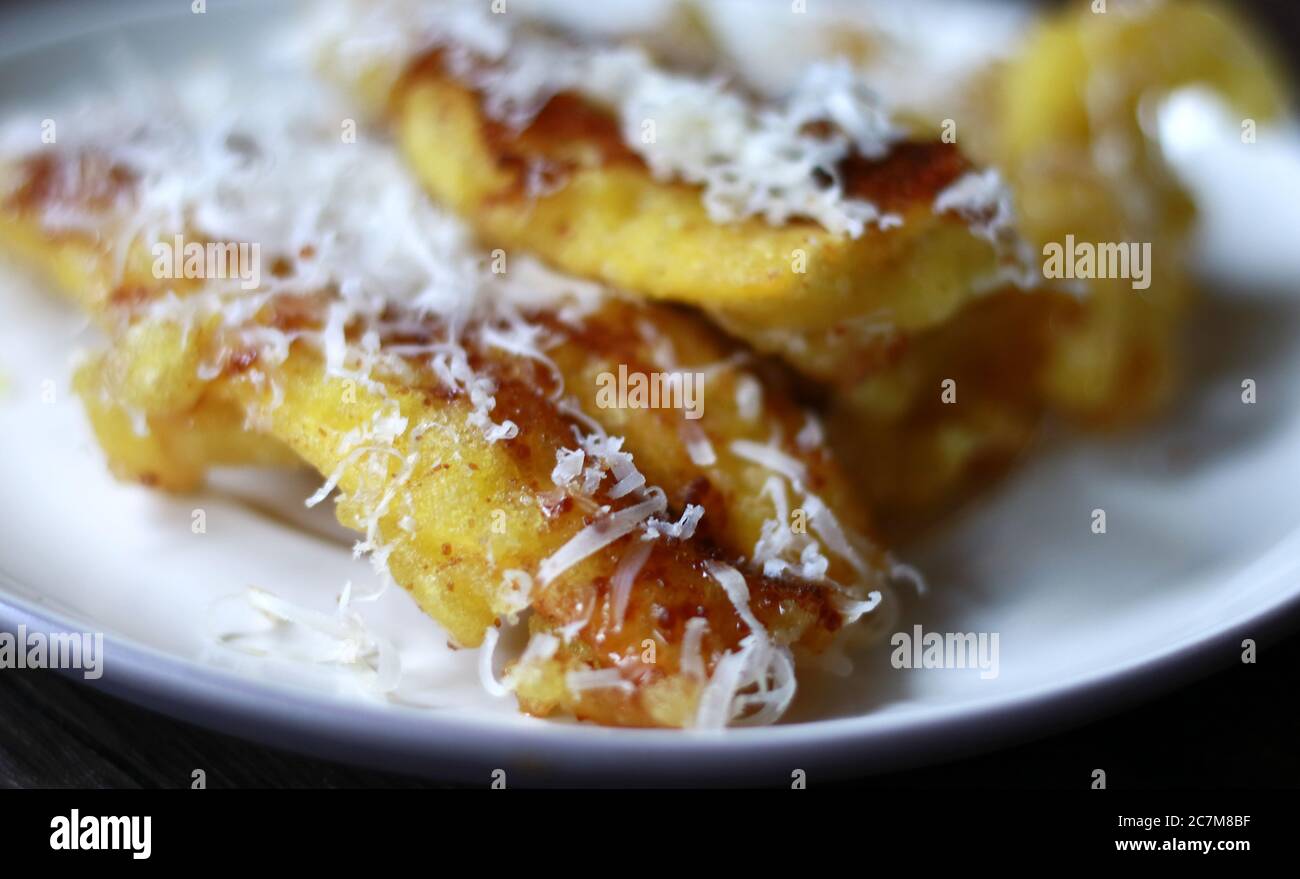 Fried banana topping chocolate, milk and cheese. Popular snack in Indonesia.  Wood background Stock Photo - Alamy, image size:1300x879