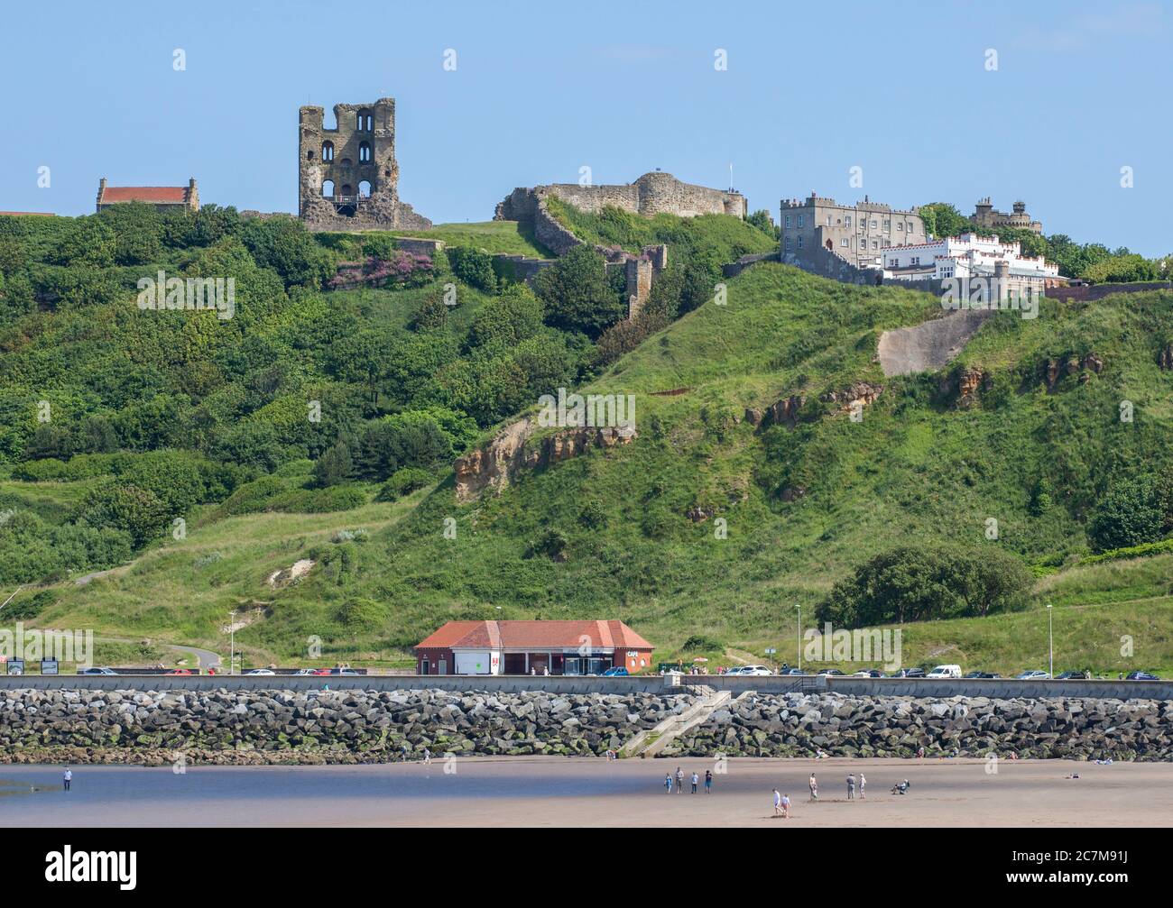 The ruins of the medieval Scarborough castle stand above the Parine Drive promenade and beach on a sunny afternoon Stock Photo