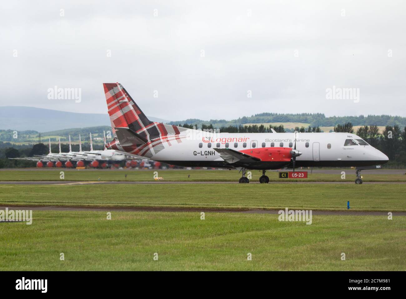 Glasgow, Scotland, UK. 17 July 2020. Pictured:  Logan Air Saab 340 Aircraft seen against a backdrop of grounded British Airways Airbus A319/A320/A321 aircraft, showing how bad the coronavirus (COVID19) crisis has affected the global airline industry.  British Airways today axed all of its Boeing 747 services cutting back and have already axed a quarter of its staff due to the pandemic. Credit: Colin Fisher/Alamy Live News. Stock Photo