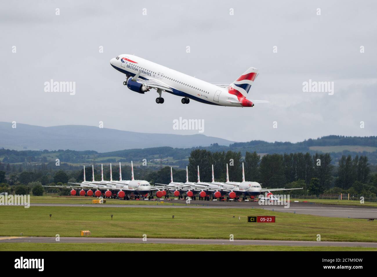 Glasgow, Scotland, UK. 17 July 2020. Pictured:  Grounded British Airways Airbus A319/A320/A321 aircraft form the backdrop showing how bad the coronavirus (COVID19) crisis has affected the global airline industry, as a BA Airbus A320 Neo shuttle service seen departing Glasgow International Airport for London.  British Airways today axed all of its Boeing 747 services cutting back and have already axed a quarter of its staff due to the pandemic. Credit: Colin Fisher/Alamy Live News. Stock Photo