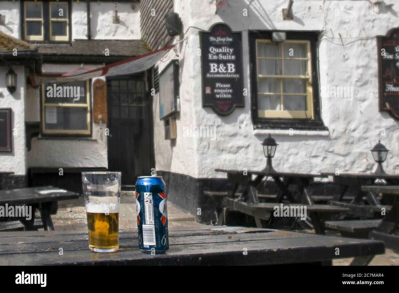 COVID19 March 2020 lockdown Pubs closed outside tables empty Half drunk pint of lager with can on table symbol of abandonment and loss of socialising Stock Photo