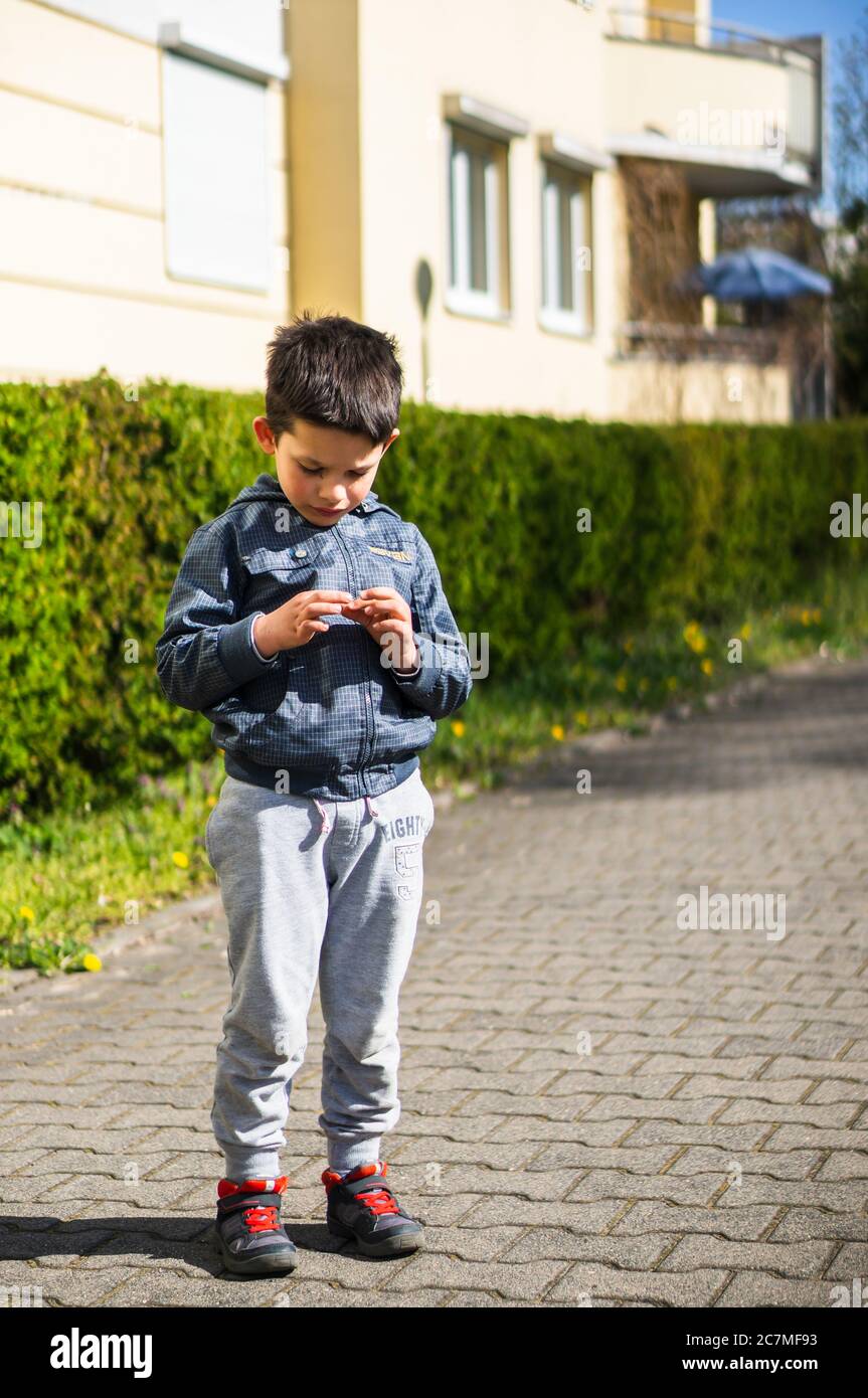 POZNAN, POLAND - Apr 12, 2020: Small young Polish Caucasian boy picking  something up from the ground on a street on a sunny spring day Stock Photo  - Alamy