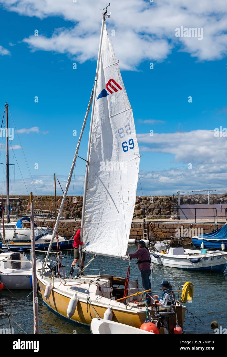 People putting up sail on a sailboat in harbour, North Berwick, East Lothian, Scotland, UK Stock Photo