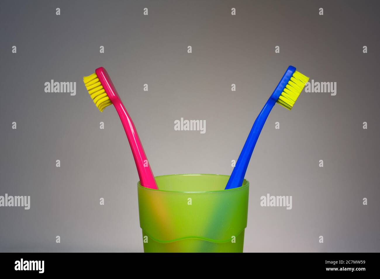 Blue and pink toothbrushes in cup. Metaphor of relationship of heterosexual love couple - argument and disagreement, conflict with lack of communicati Stock Photo