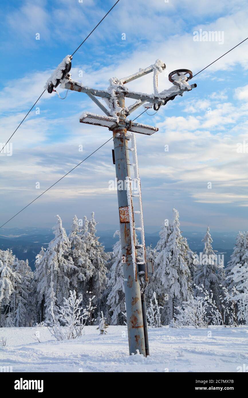 Old and rusty pole of ski tow - device for transportation in ski resort. Mechanism is surrounded by winter nature Stock Photo