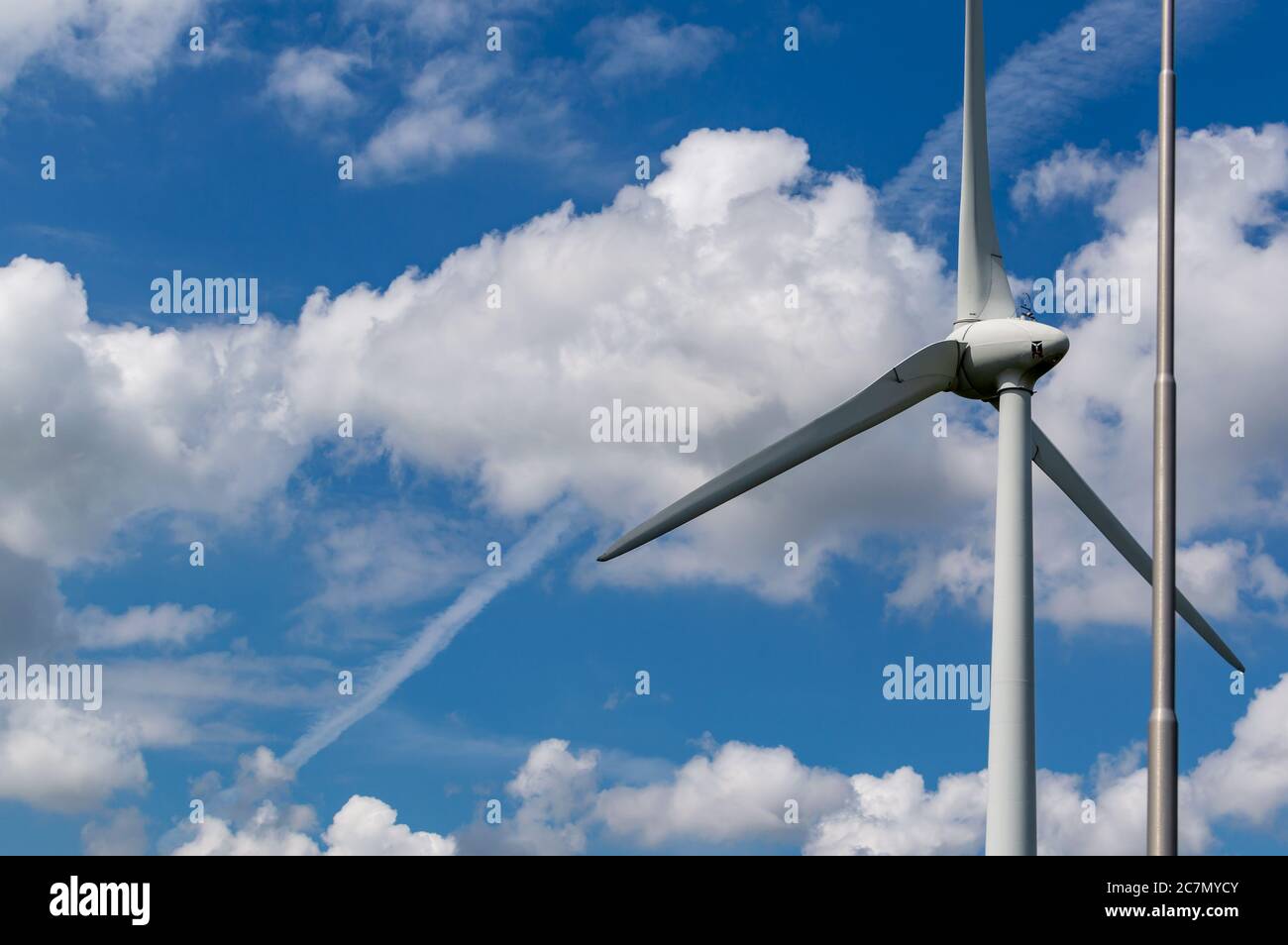 Wind turbine with a backdrop of clouds and a blue sky Stock Photo