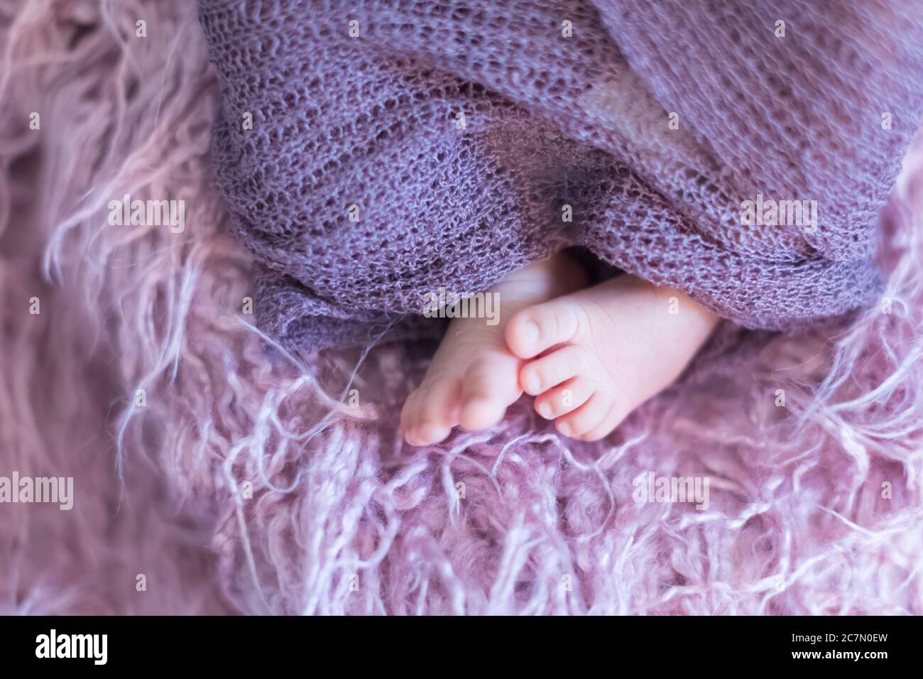 Baby feet swaddled in purple fabrics Stock Photo