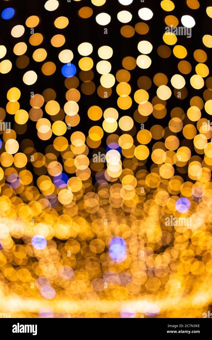 Christmas xmas round bokeh abstract vertical view background with yellow golden circles illuminated decorations hanging lights at night in Warsaw, Pol Stock Photo