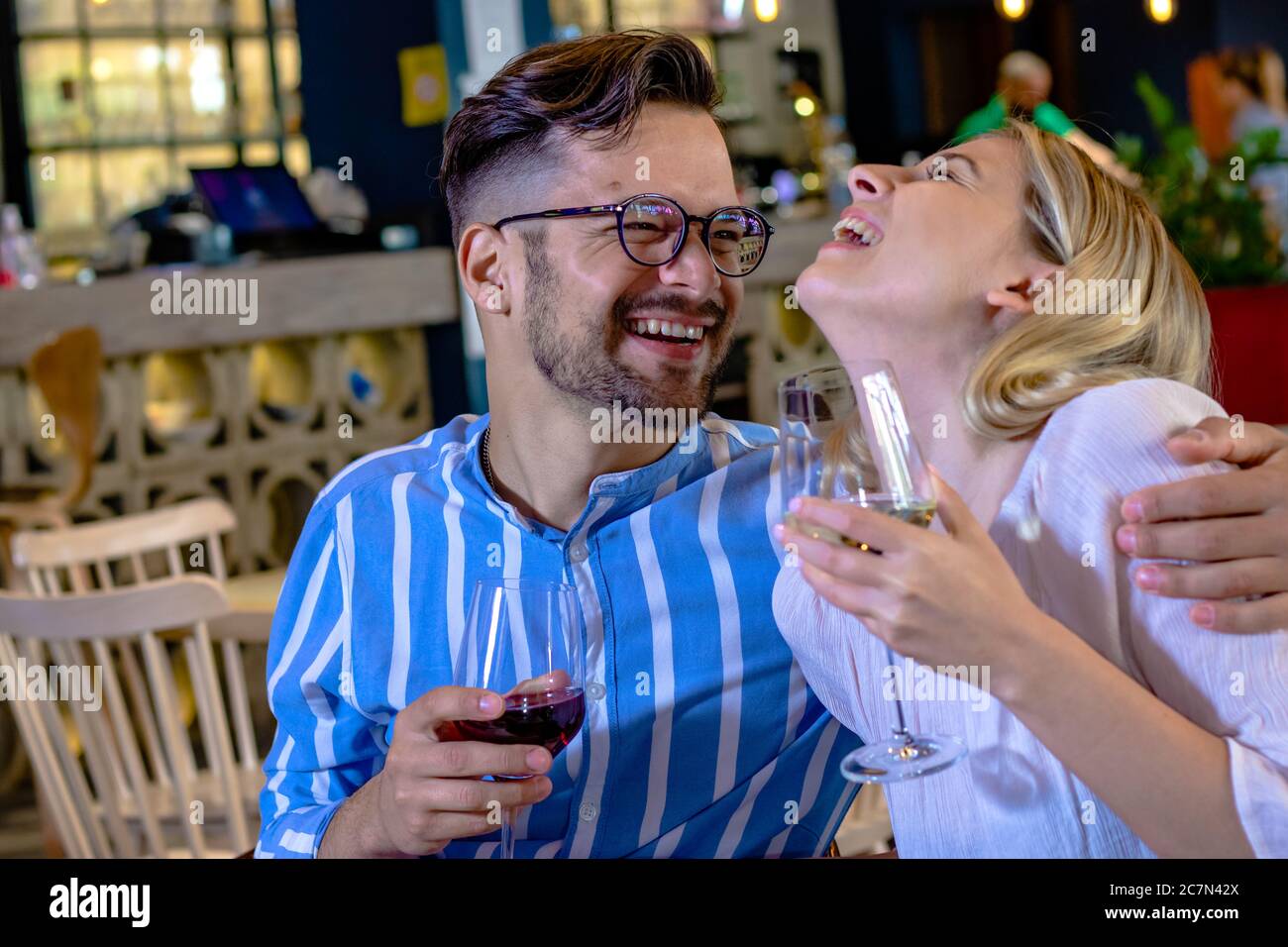 Happy young romantic couple in love, drinking wine, smiling and