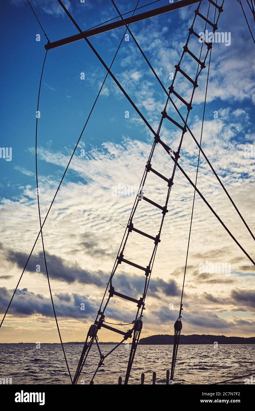 Old schooner rope ladder and rigging silhouette at sunset, color toning applied. Stock Photo