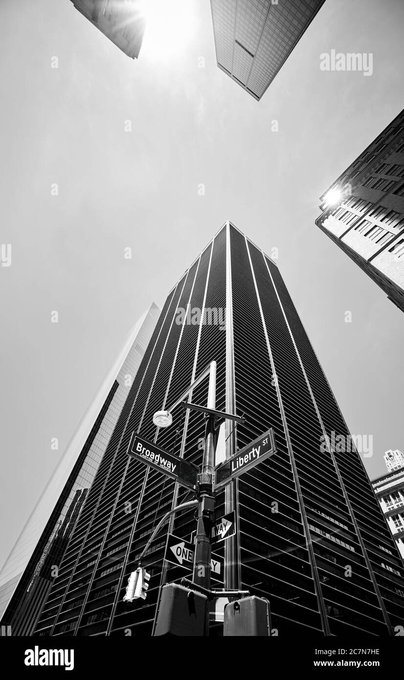 Looking up at Broadway and Liberty street sign with buildings in background against the sun, lens flare effect, New York City, USA. Stock Photo
