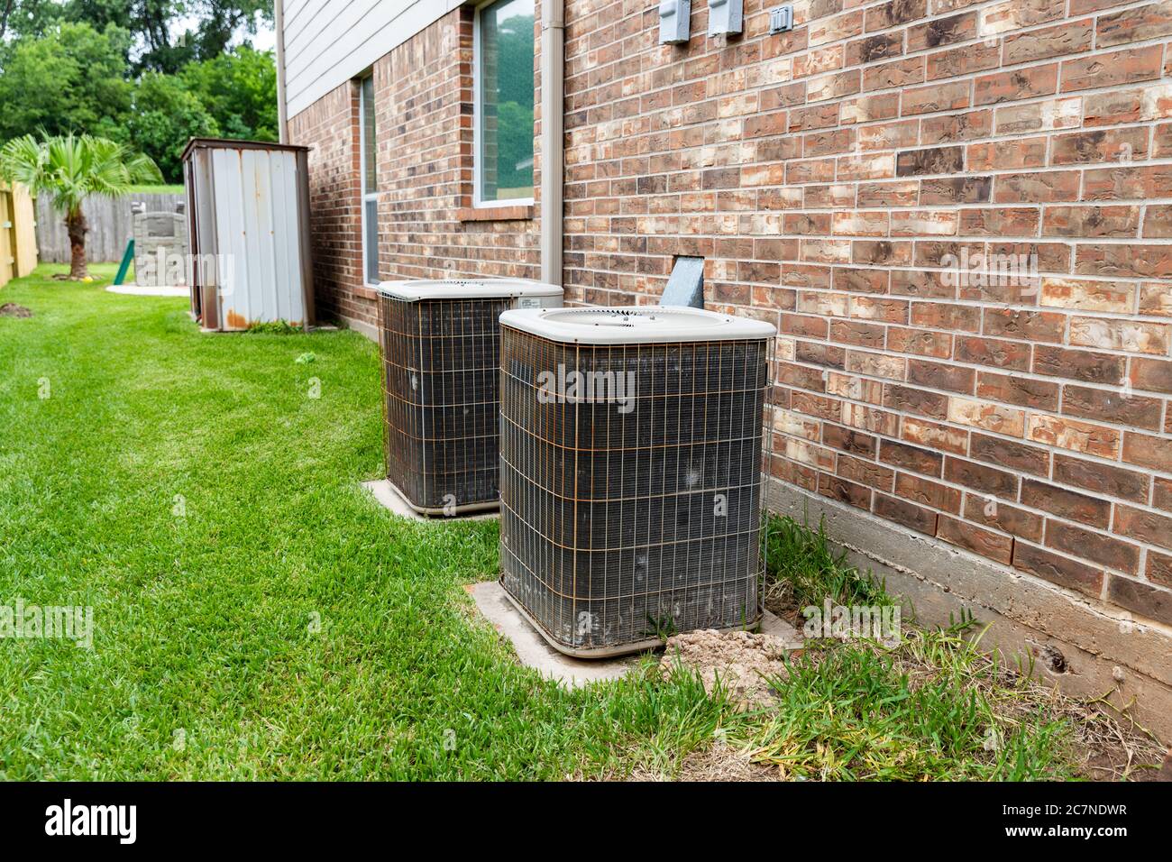 Older air conditioner units next to brick home with copy space Stock