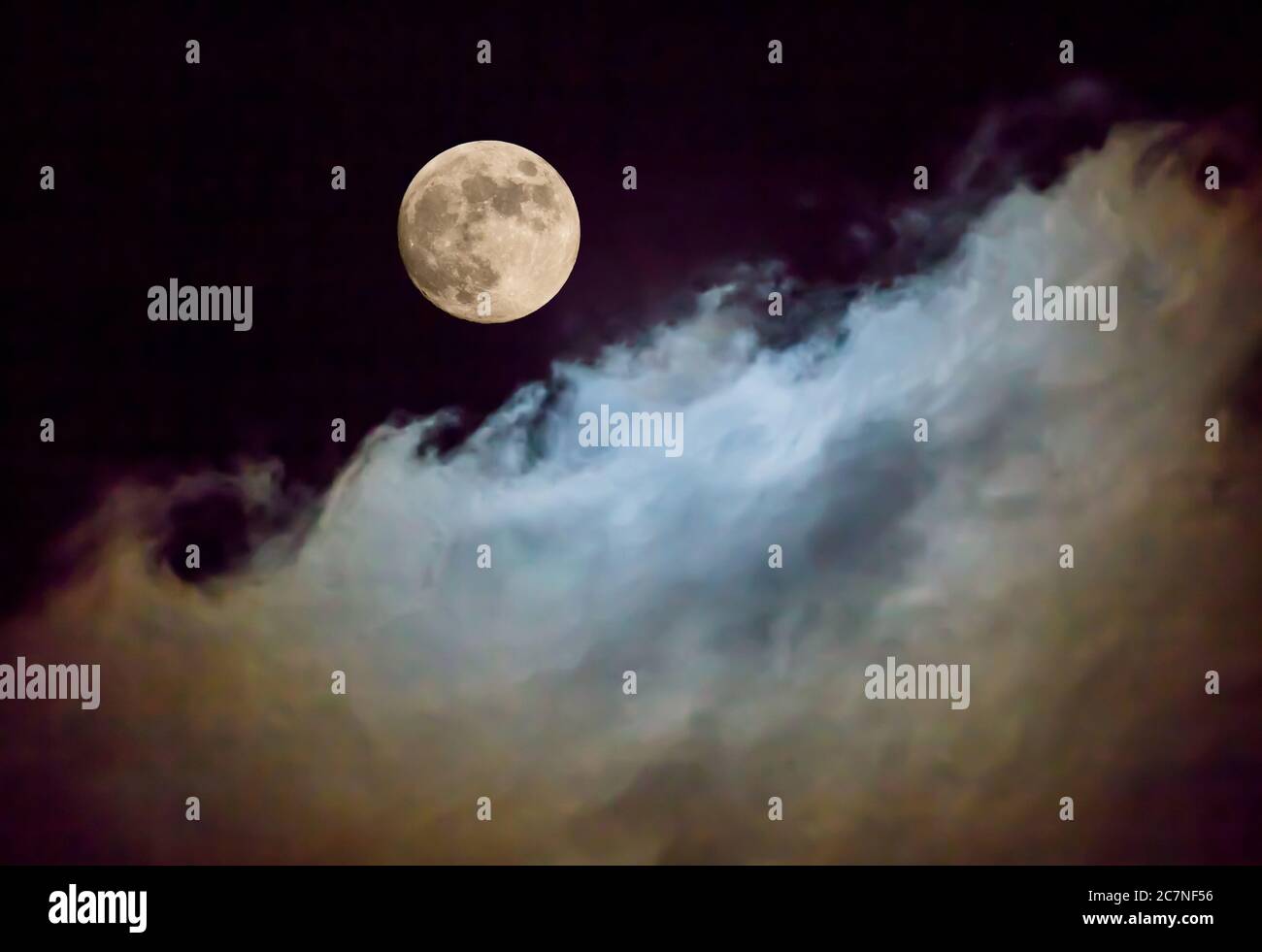 A full moon illuminates passing clouds in a night sky. Stock Photo