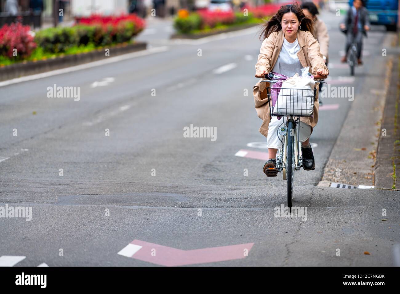 Kyoto, Japan - April 17, 2019: Japanese person woman on bicycle riding bike on street candid city life in traffic road lane Stock Photo