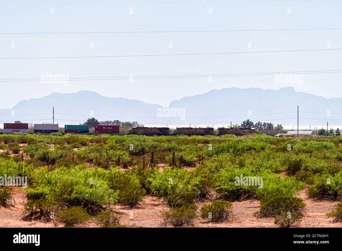 Tularosa, USA - June 8, 2019: New Mexico Sacramento Mountains silhouette in Otero county with cargo train on tracks and sign for Kline shipment Stock Photo