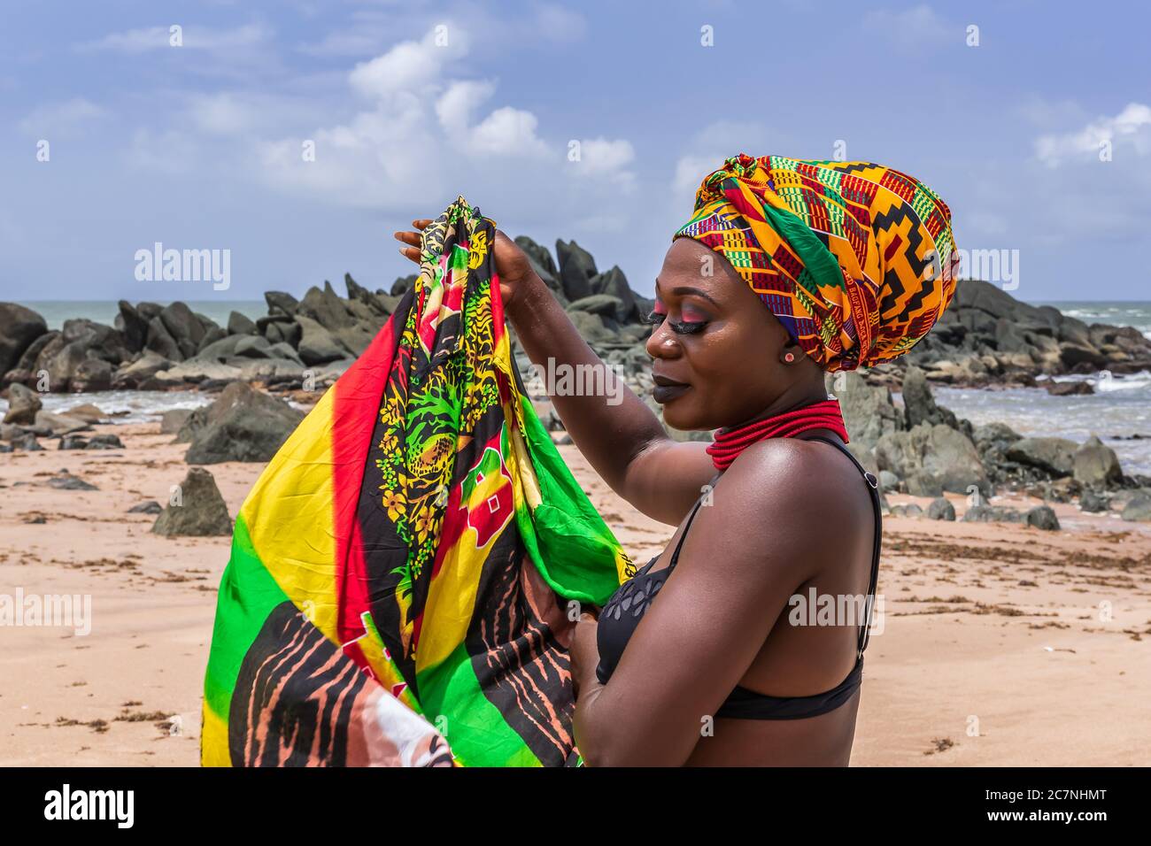 Ghana woman on the beautiful beach of Axim, located in Ghana West Africa. Headdress in traditional colors from Africa. Stock Photo