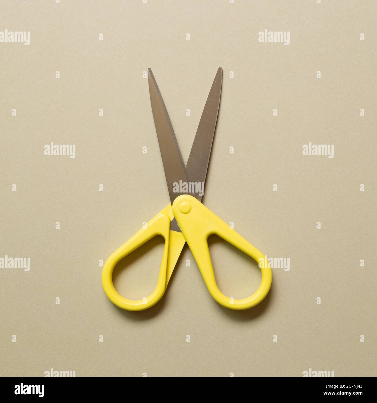 Yellow scissors isolated on beige background. top view Stock Photo