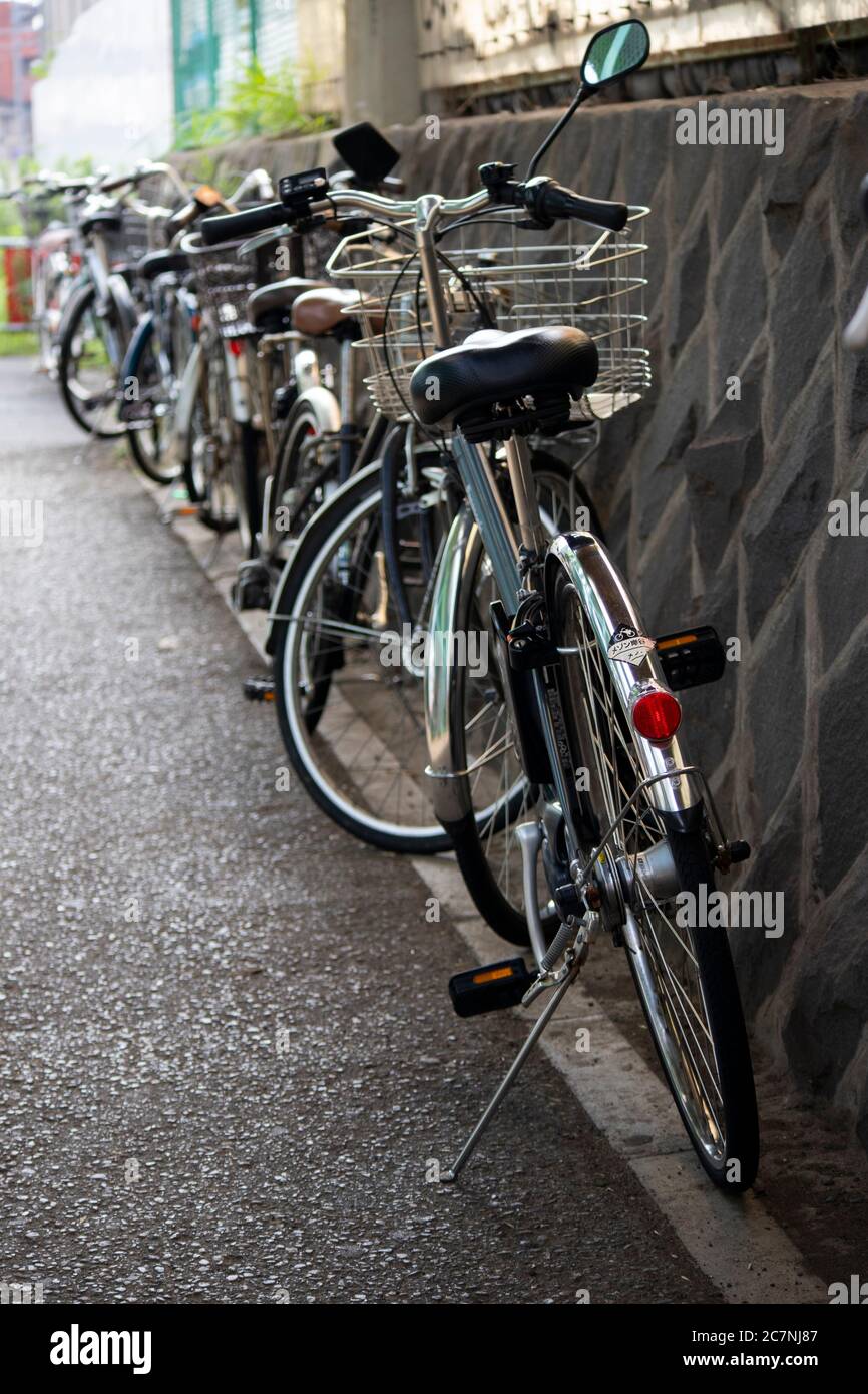 Bicycles parked at the side of the walkway nearby the train station in Japan. Stock Photo