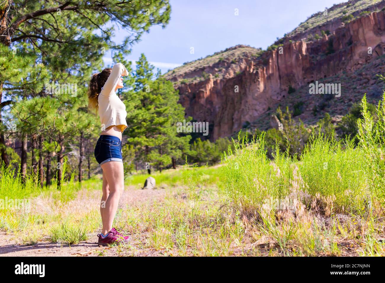Main Loop trail with woman standing looking up hiking in Bandelier National Monument in New Mexico in Los Alamos with canyon cliffs Stock Photo