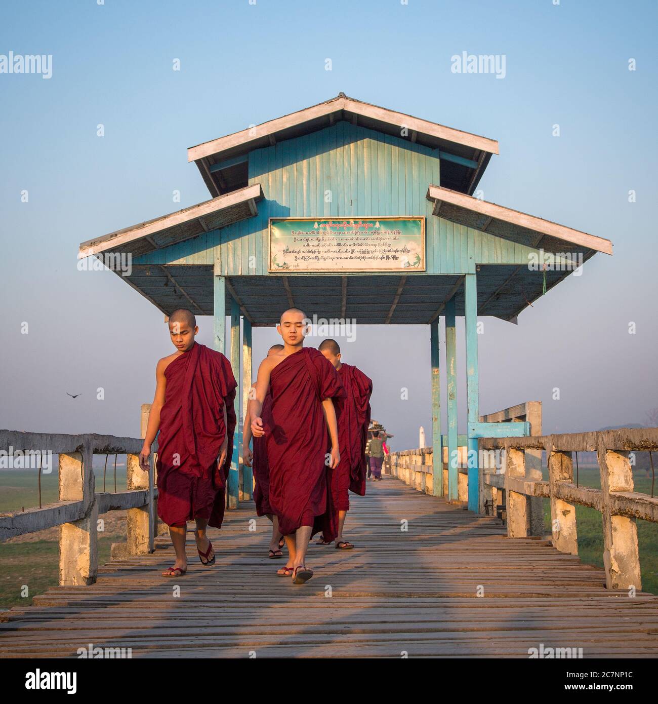 Young monks walk on the U Bein Bridge in Mandalay, Myanmar Stock Photo