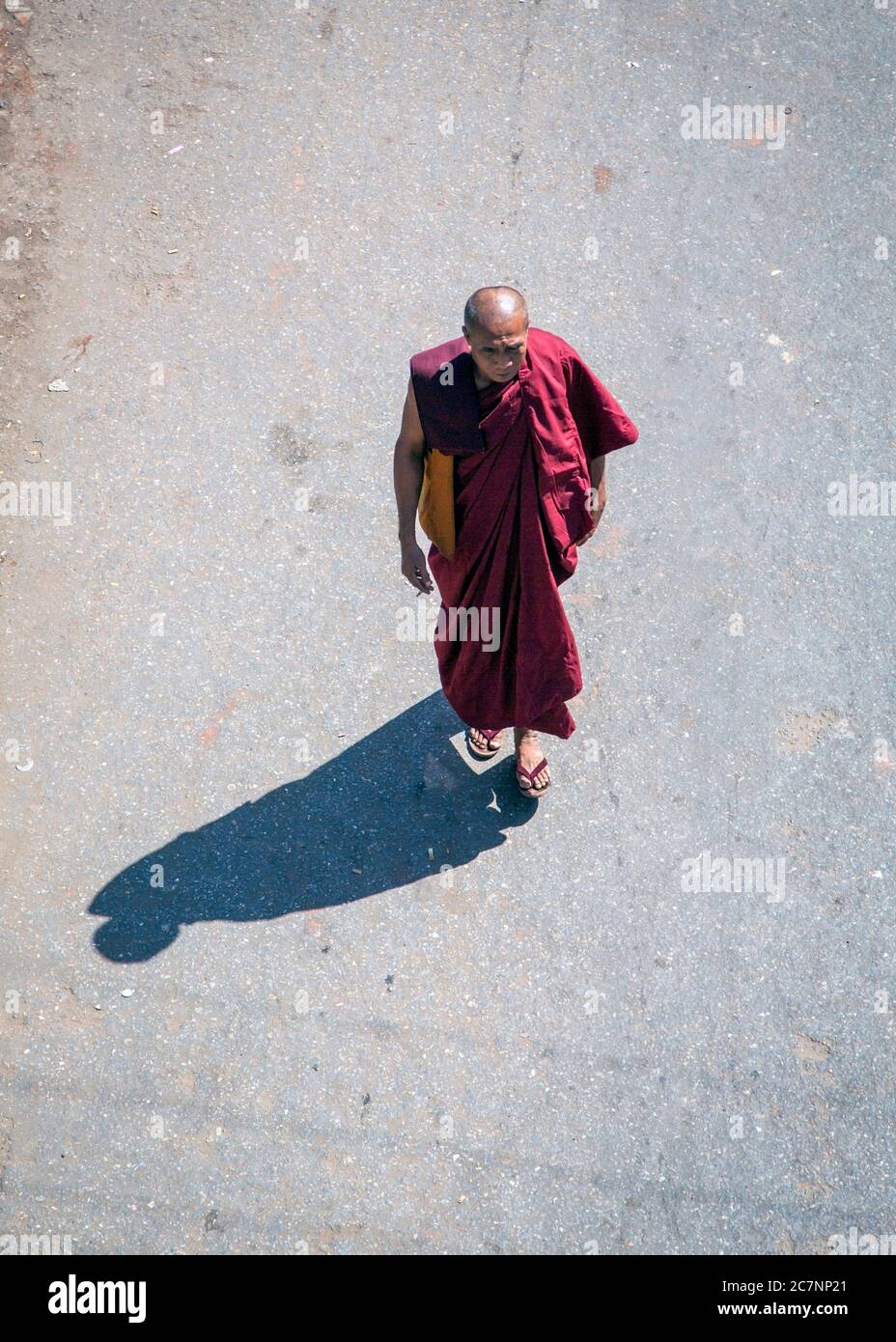 An overhead view of a Buddhist monk walking on a road in Mandalay, Myanmar Stock Photo