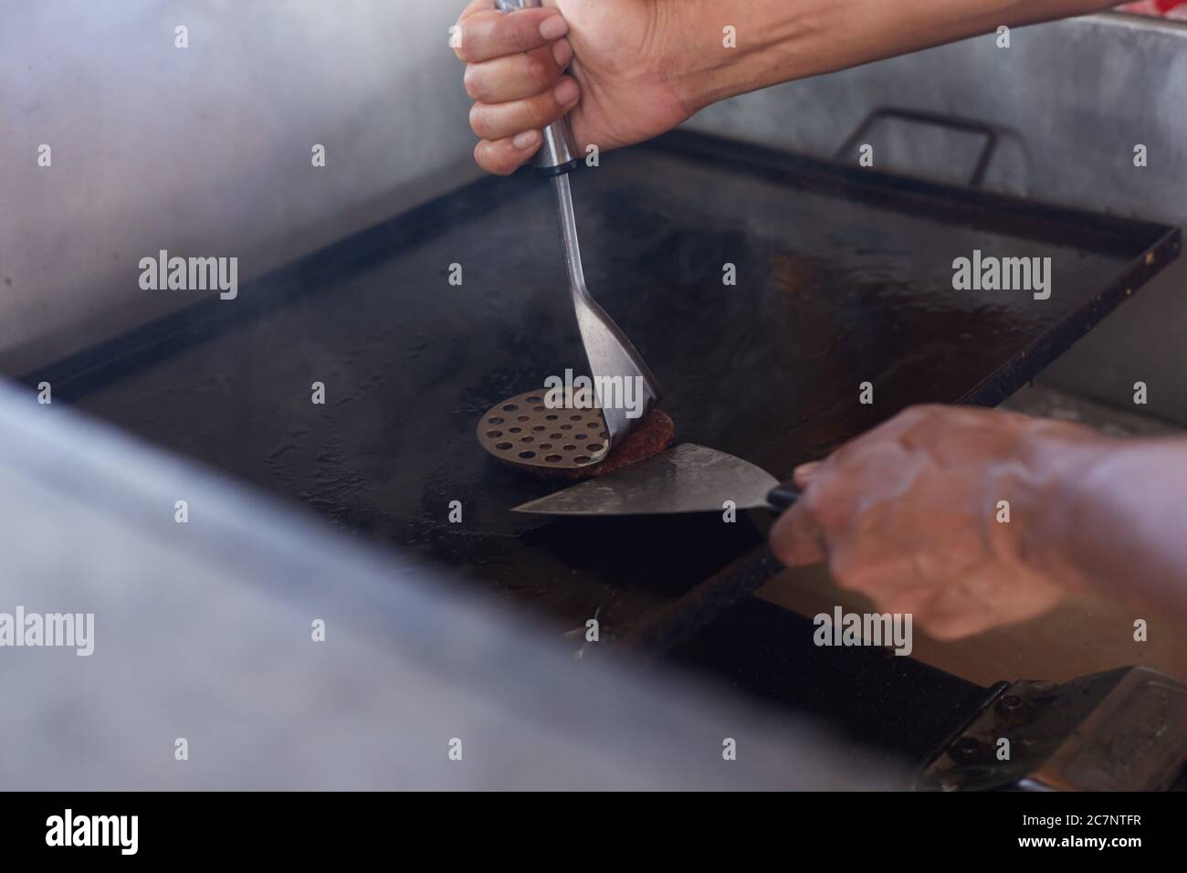 man cooking hamburgers at beach bar Stock Photo