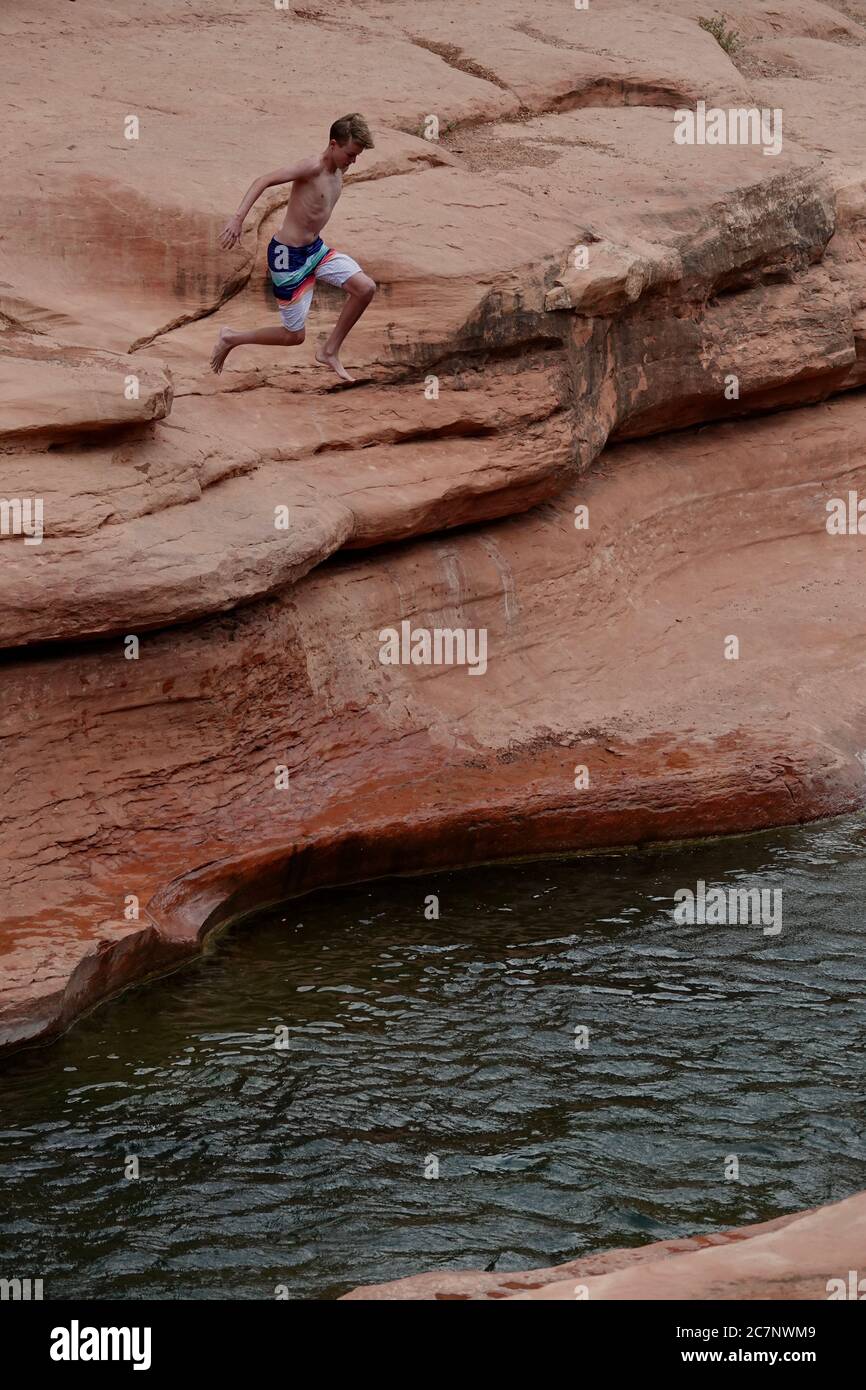A teenage Boy goes cliff jumping at Slide Rock State Park in Sedona, Arizona during summer. Stock Photo