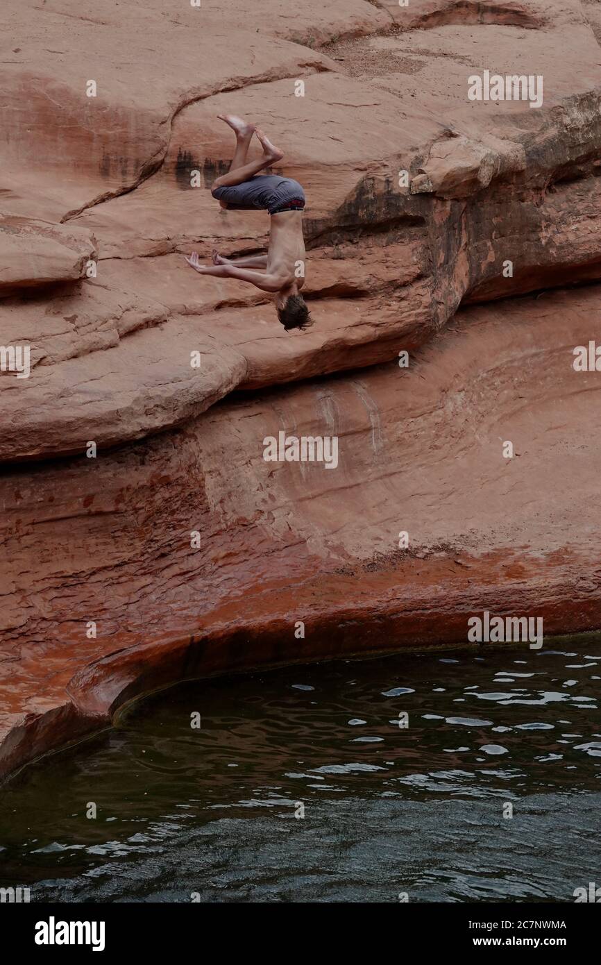 A teenage Boy goes cliff jumping and does a flip in the air at Slide Rock State Park in Sedona, Arizona during summer. Stock Photo