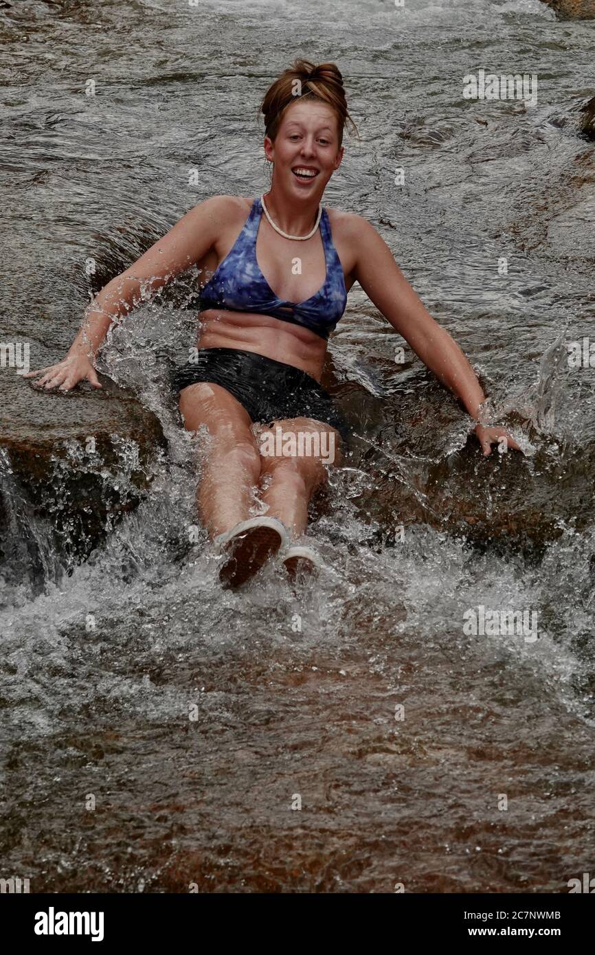 A teenage girl slides down a natural water slide at Slide Rock State Park in Sedona, Arizona during summer. Stock Photo