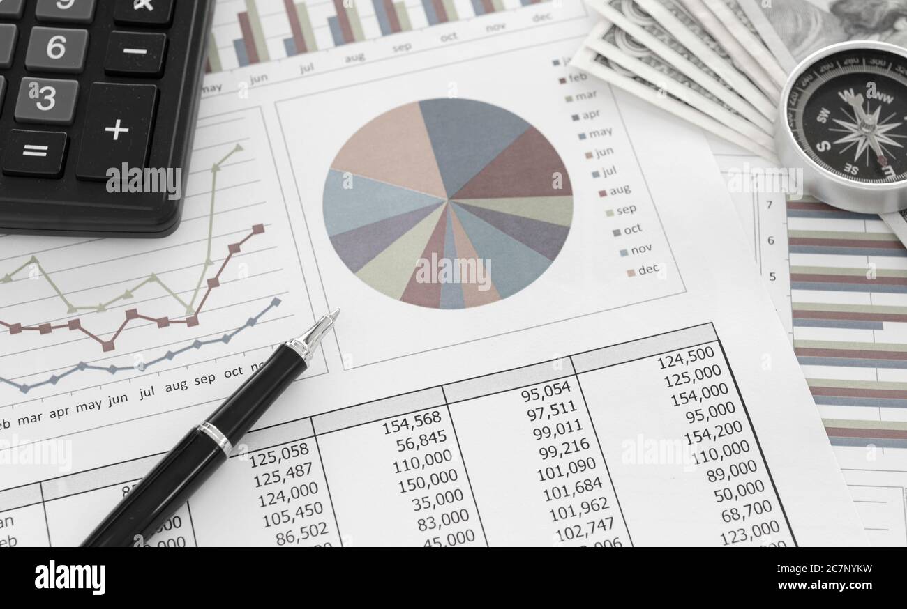 Pen on Pie chart and graphs business report with money, compass