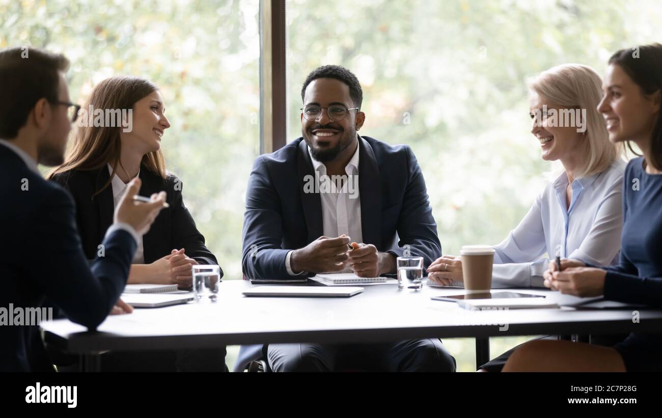 Five multiethnic company staff gather together talking planning future project Stock Photo