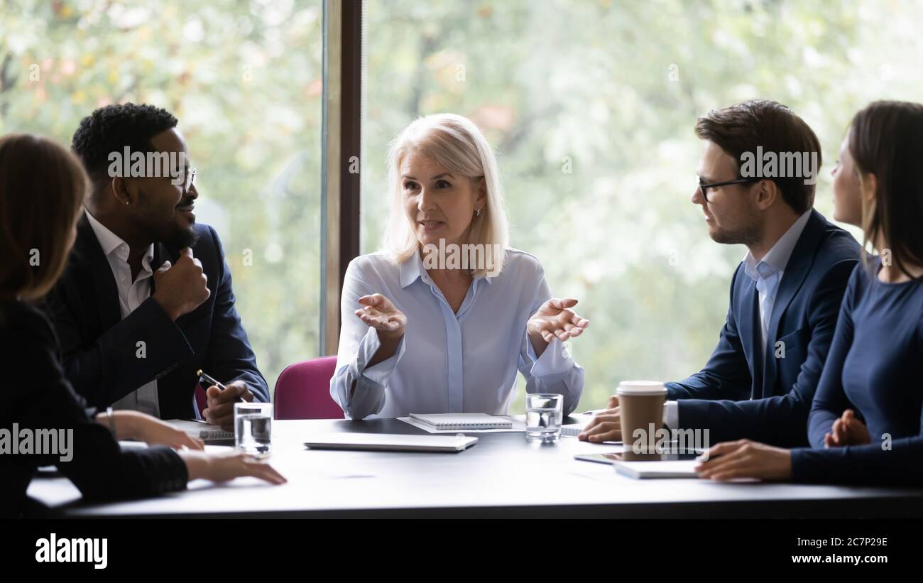Mature leader boss give helpful information to young diverse professionals Stock Photo
