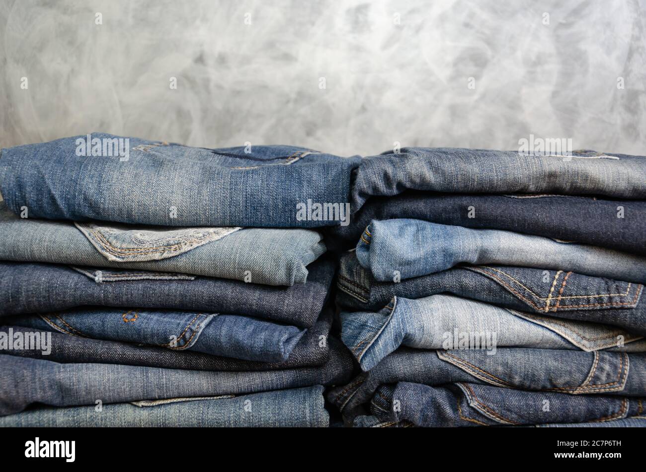 Carelessly folded jeans in two piles on a gray background. Close-up of jeans in different colors. Jeans texture or denim background. Copy space Stock Photo
