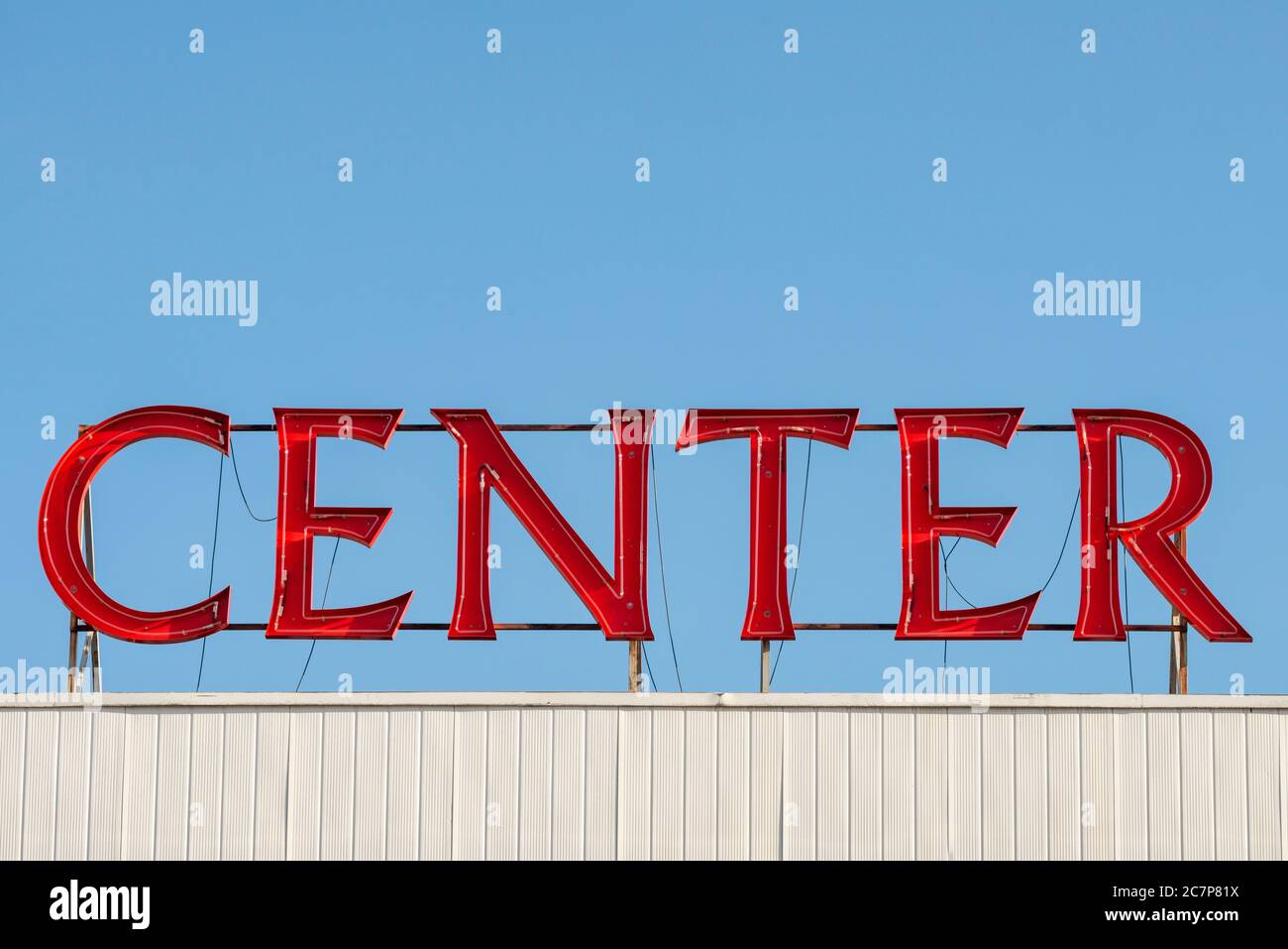 Luminous and vivid Center writing and red LED neon logo sign on building roof against blue sky Stock Photo