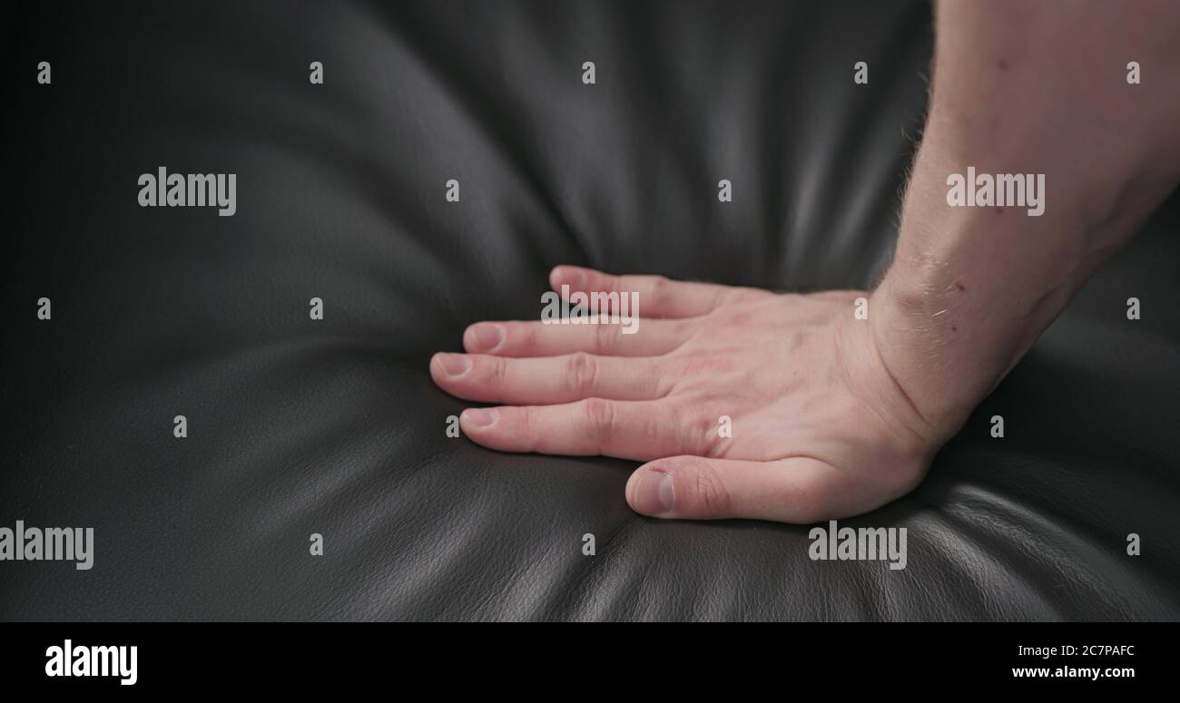 man hand checking dark brown leather cushion closeup Stock Photo