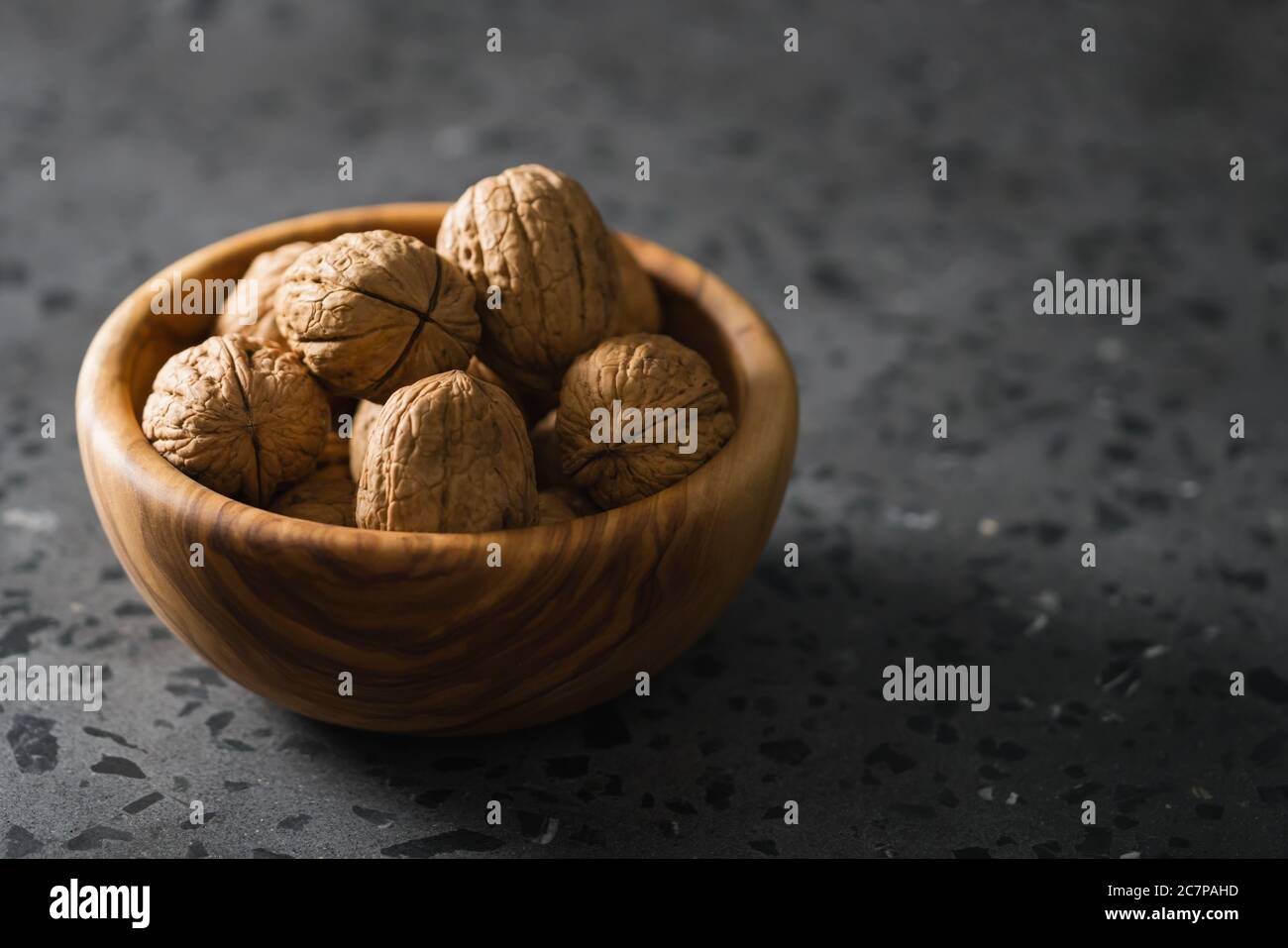 inshell walnuts in olive wood bowl on terrazzo countertop Stock Photo