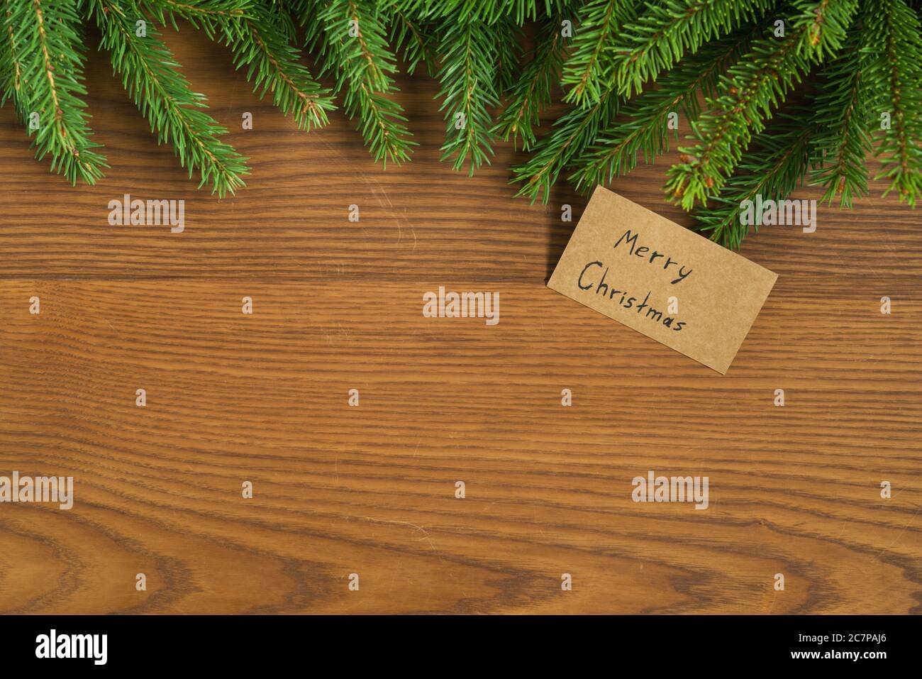 Flat lay christmas background with spruce twigs and merry christmas card on ash wood surface Stock Photo