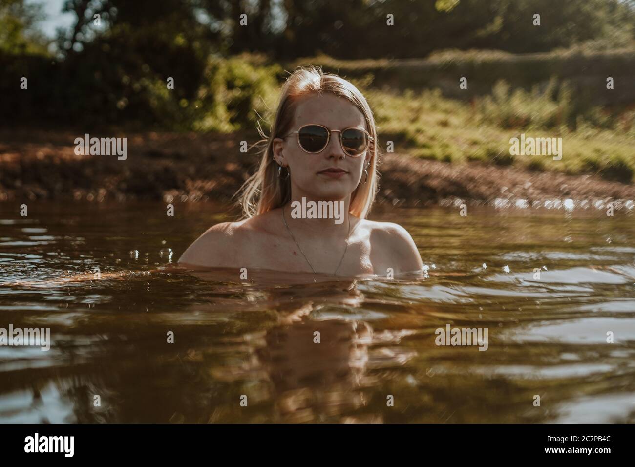Beautiful woman skinny dipping and wild swimming in river Stock Photo