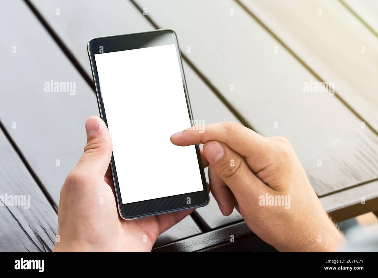 Man holding smart mobile phone on wooden table background Stock Photo