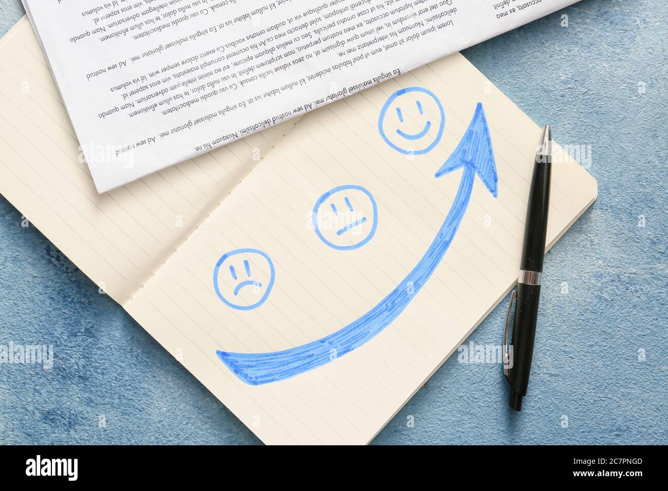 Notebook with drawn sad, happy and neutral faces and newspaper on color ...
