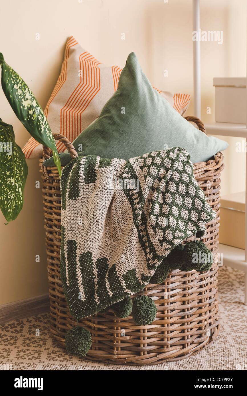 Basket with pillows and plaid in room Stock Photo Alamy