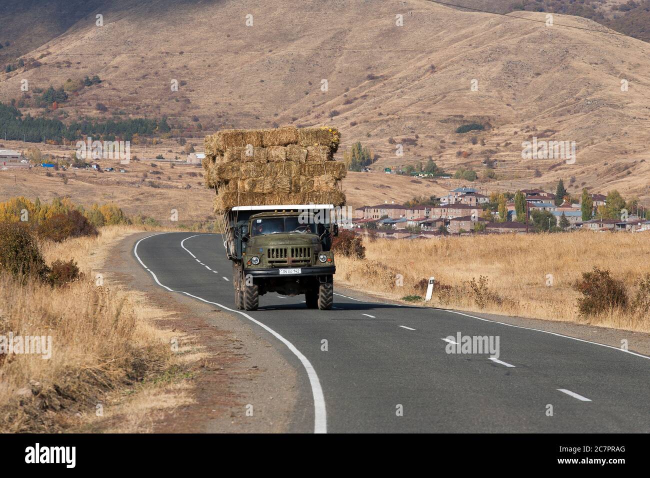 Trucks of shapes and sizes move large goods around Armenia, such as this farm truck transporting bales of hay. Stock Photo