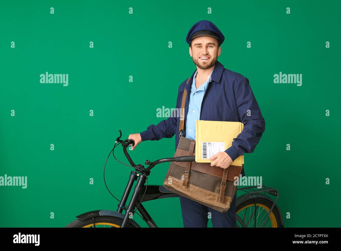 Handsome young postman with bicycle on color background Stock Photo