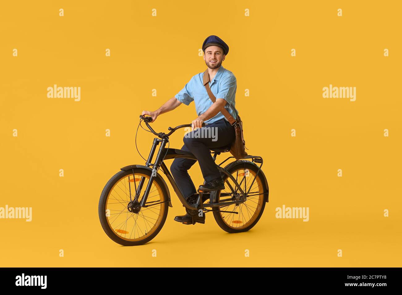 Handsome young postman with bicycle on color background Stock Photo