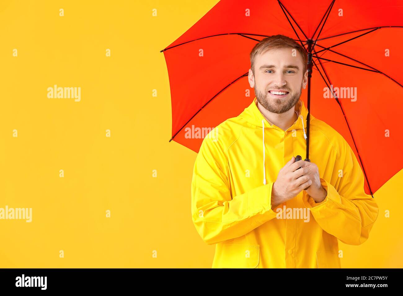Handsome young man with umbrella on color background Stock Photo - Alamy